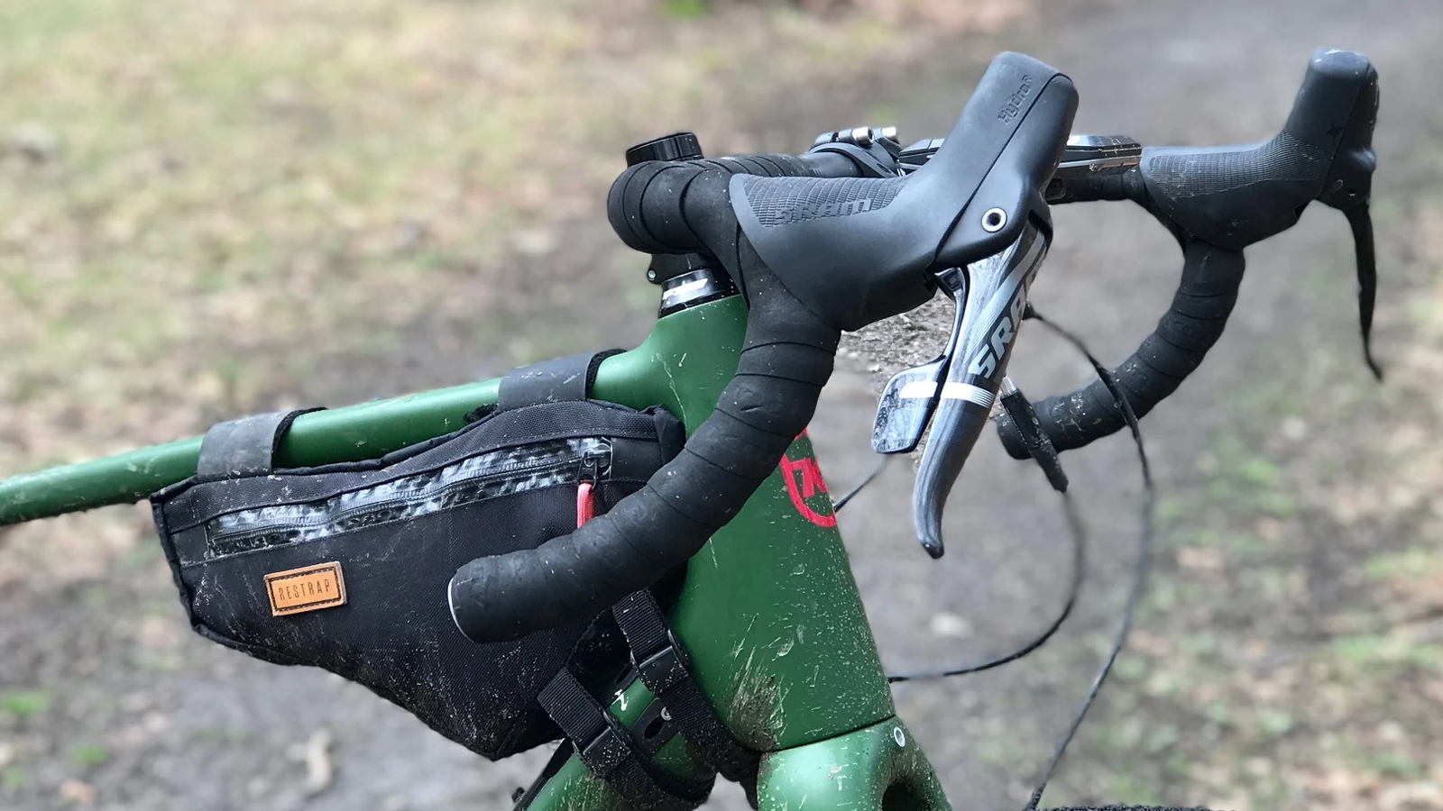 Una bicicleta gravel verde con una bolsa de cuadro con tubo superior y manillares ensanchados