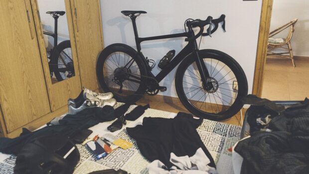 A black bike and various cycling kit laid out in a room