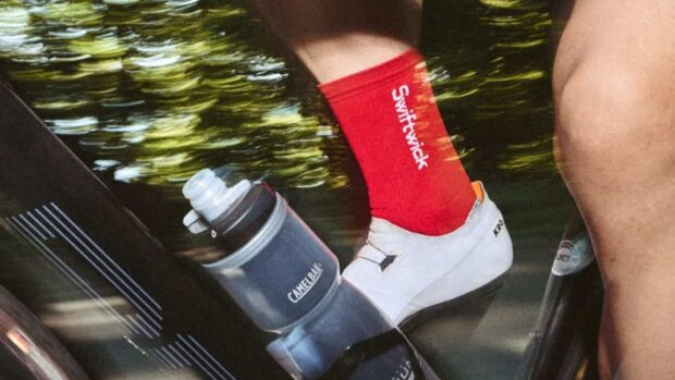 A close up shot of a cyclists riding a BMC bike wearing red Swiftwick socks