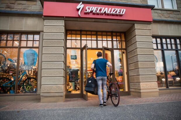 A cyclist walks their bike into a specialized shop