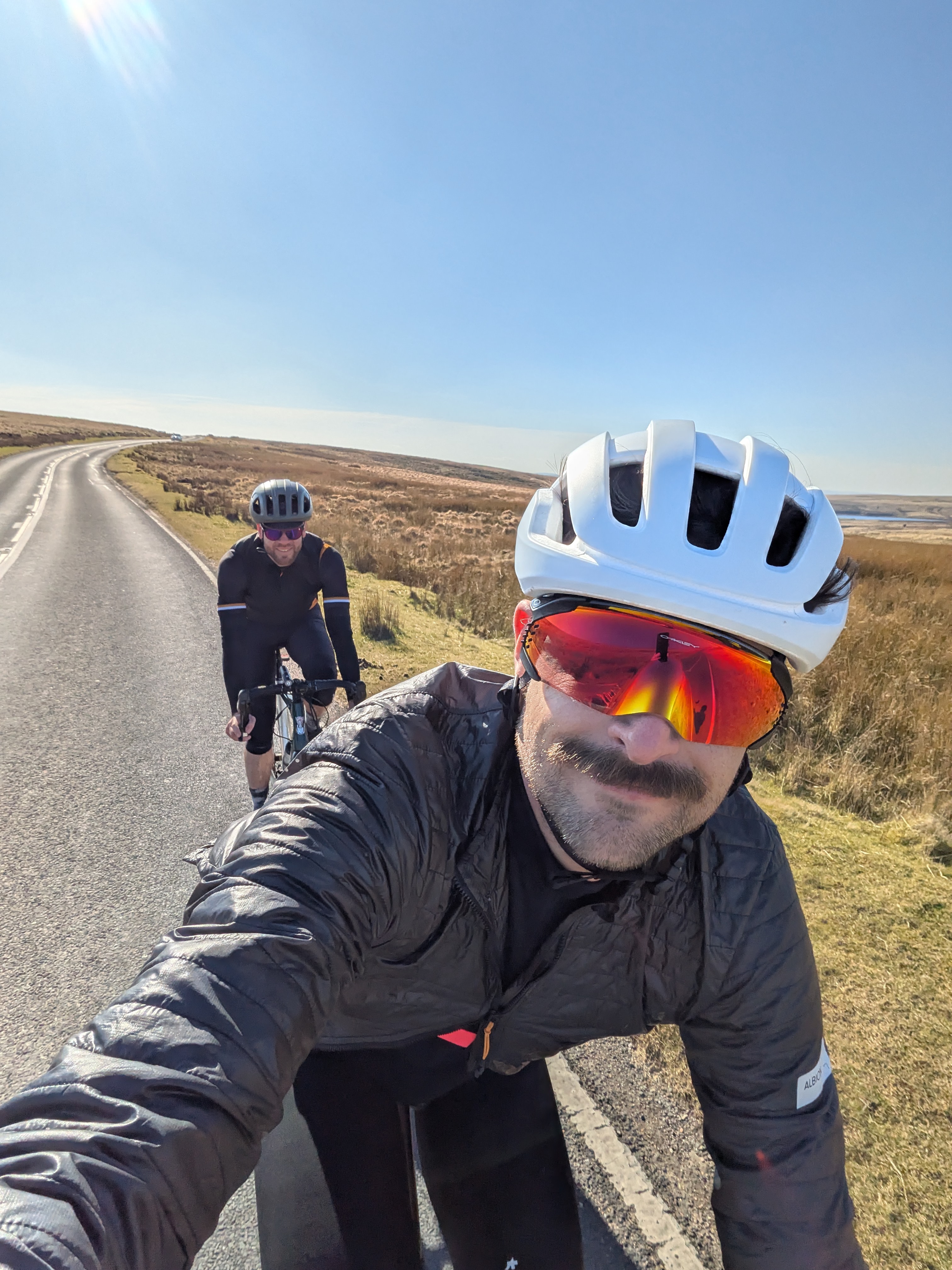 Un hombre que lleva el ciclismo de Oakley Velo Kato en un camino seco y tomando una selfie