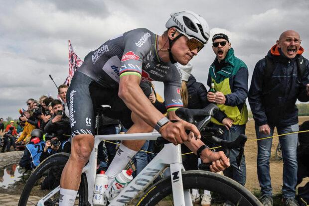Mathieu van der Poel with a look of determination while riding to victory in Paris-Roubaix with fans shouting in the background