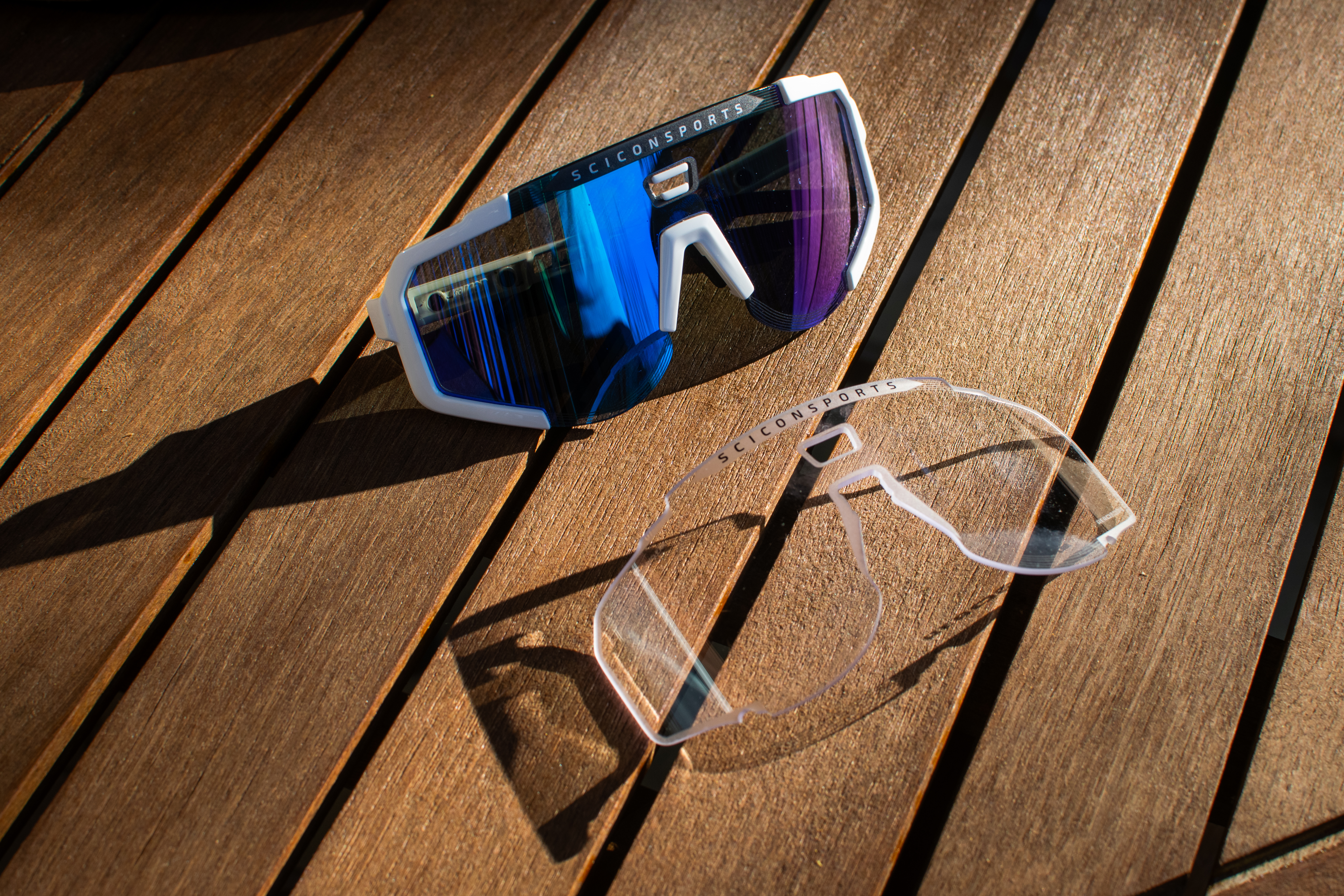 Un par de gafas de sol de aerocopio de Scicon y lente transparente en una mesa de madera