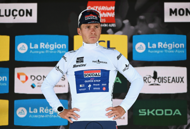 Remco Evenepoel with hands on hips looks pensive on the podium as best young rider