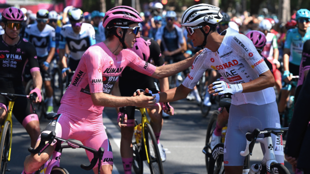 Simon Yates, wearing a full pink kit, shaking hands with Isaac del Toro