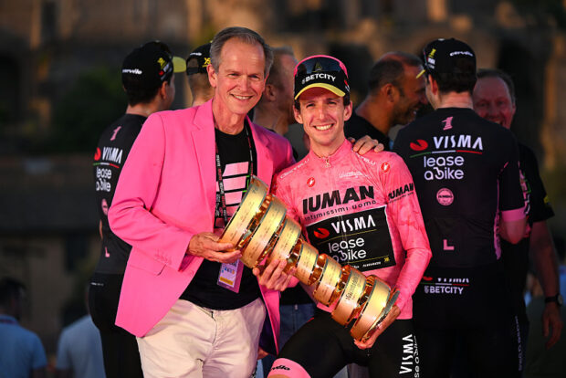 Richard Plugge in a pink blazer with Giro winner Simon Yates holding the Trofeo Senza Finé trophy
