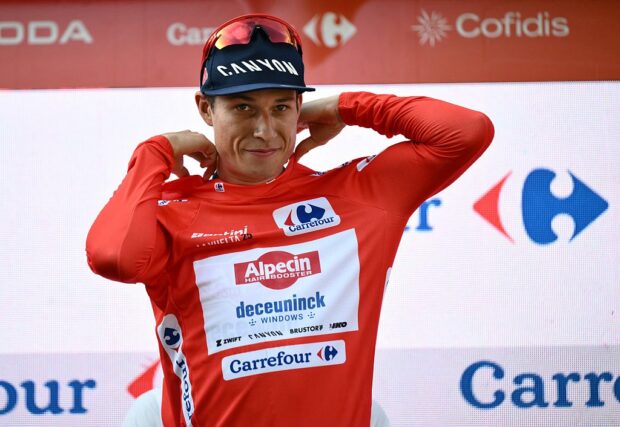 Team Alpecin's Belgian rider Jasper Philipsen puts on the red jersey of the overall leader on the podium of the first stage of the Vuelta a Espana, a 183 km race between Torino - Reggia di Venaria and Novara, in Italy's Piemonte region, on August 23, 2025. (Photo by Marco BERTORELLO / AFP)