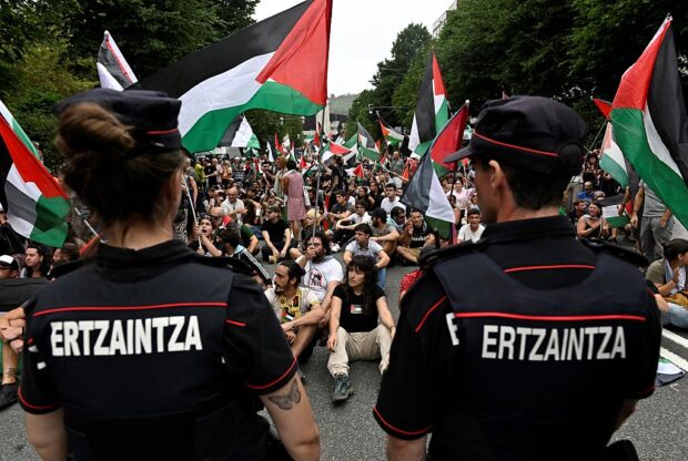 Pro-Palestinian protesters holding Palestinian and Basque flags demonstrate next to Basque regional police 'Ertzaintza' officers, following the Vuelta a España stage 11, in Bilbao.