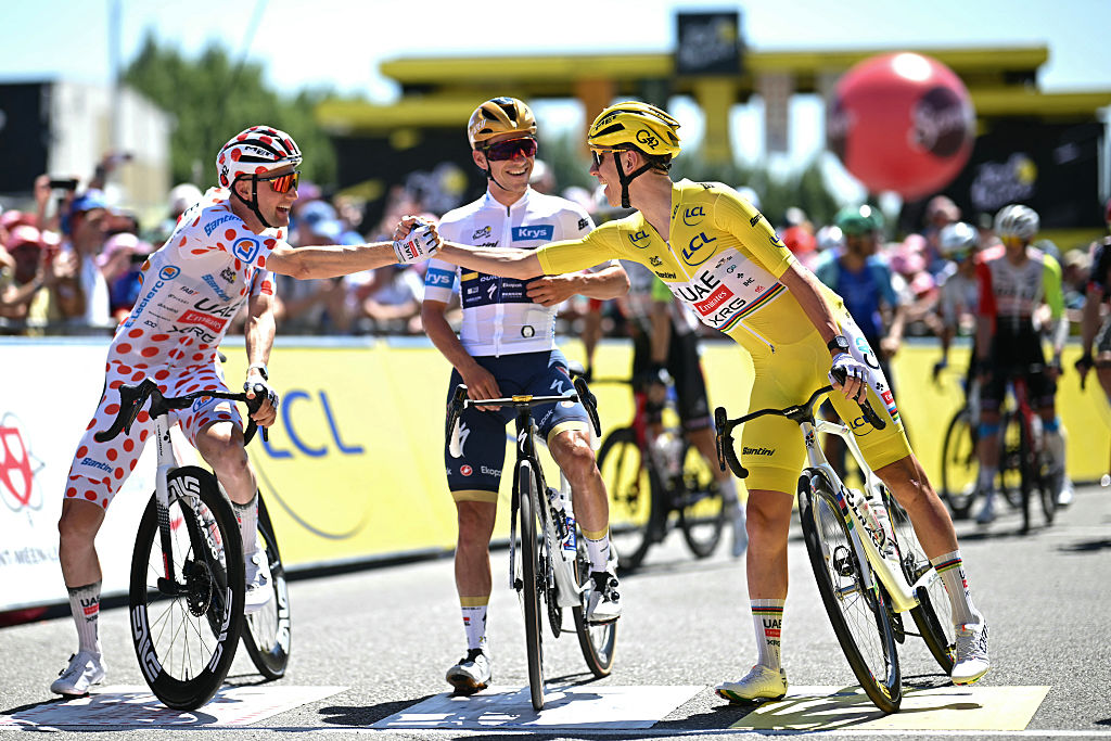 Guest, UAE Team Emirate - XRG team's Belgian rider Tim Wellens wearing the best climber's polka dot (dotted) jersey (L) shakes hands with UAE Team Emirates - XRG team's Slovenian rider Tadej Pogacar wearing the overall leader's yellow jersey (R) as Soudal Quick-Step El piloto belga Remco Evenepoel del equipo con la mejor camiseta blanca (c) de la mejor jinete de jóvenes. Venance/AFP a través de Getty Images)