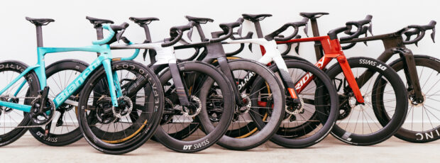 Six aero bikes lean against a wall