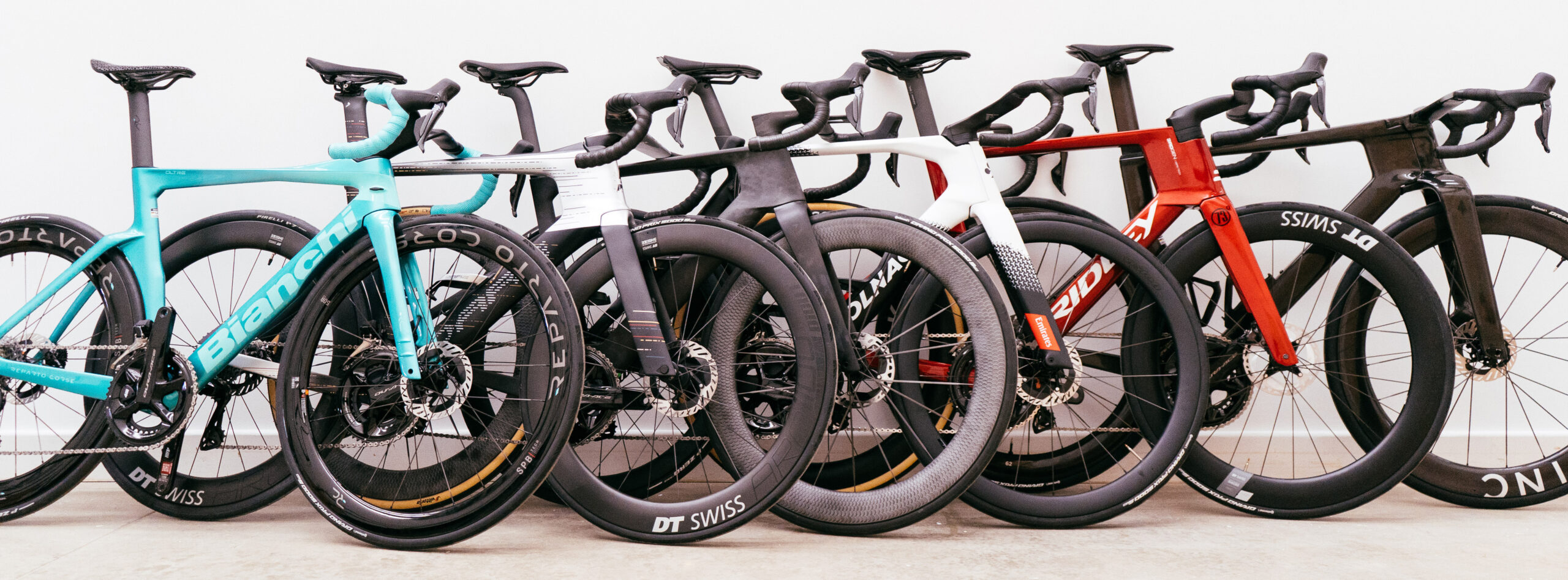 Six aero bikes lean against a wall