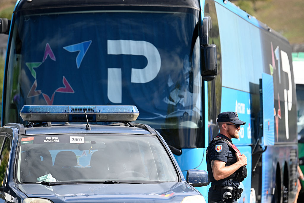 A National Police officer stands guard next to Team Israel Premier Tech's bus in Vegadeo at the start of the 15th stage of the Vuelta a Espana cycling tour, a 167 km race between A Veiga/Vegadeo and Monforte de Lemos, on September 7, 2025. (Photo by MIGUEL RIOPA / AFP)