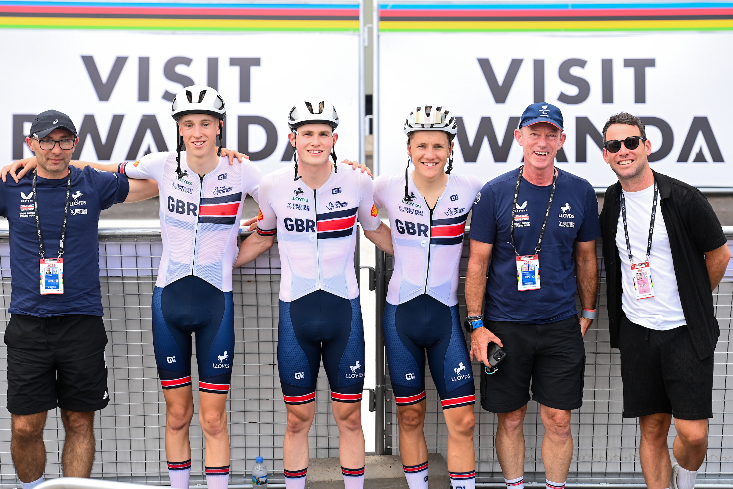 Imagen de Simon Wilkinson/Swpix.com - 26/09/2025 - Ciclismo - 2025 UCI Road World Championships - Kigali Convention Center, Kigali, Ruanda - Men Junior Road Race - Max Hinds (Gran Bretaña), Matthew Peace (Gran Bretaña), Sage de Dylan (Gran Bretaña) con miembros del equipo y ex ciclo ciclovelista British Mark Cavendish