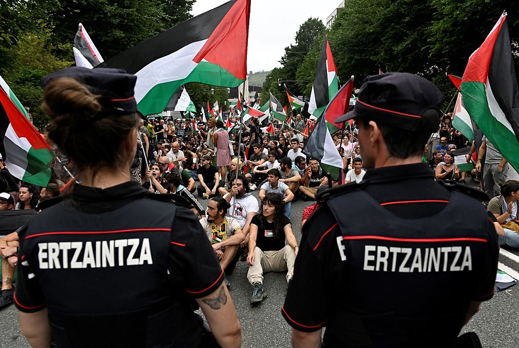 Pro-Palestinian protesters holding Palestinian and Basque flags demonstrate next to Basque regional police 'Ertzaintza' officers, following the Vuelta cycliste race 11th stage, in Bilbao, on September 3, 2025. Pro-Palestinian protest forces Vuelta stage to be shortened and to take the time at 3 kilometres before the line, according to the organisers, AFP reports. (Photo by ANDER GILLENEA / AFP)