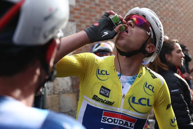 Soudal Quick-Step's Belgian rider Tim Merlier wearing the overall leader's yellow jersey drinks from a bottle after wining the 2nd stage of the Paris-Nice cycling race, 183,9 km between Montesson and Bellegarde, on March 10, 2025. (Photo by Anne-Christine POUJOULAT / AFP)