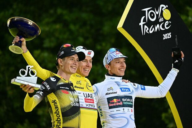 Overall winner UAE Team Emirates - XRG team's Slovenian rider Tadej Pogacar (C) wearing the overall leader's yellow jersey, second-placed Team Visma - Lease a bike team's Danish rider Jonas Vingegaard (L), and third-placed Red Bull - BORA - hansgrohe team's German rider Florian Lipowitz (R) celebrate on the podium after the 21st and final stage of the 112th edition of the Tour de France cycling race, 132.3 km between Mantes-la-Ville and Paris Champs-Ãlysees, on July 27, 2025. (Photo by Loic VENANCE / AFP)