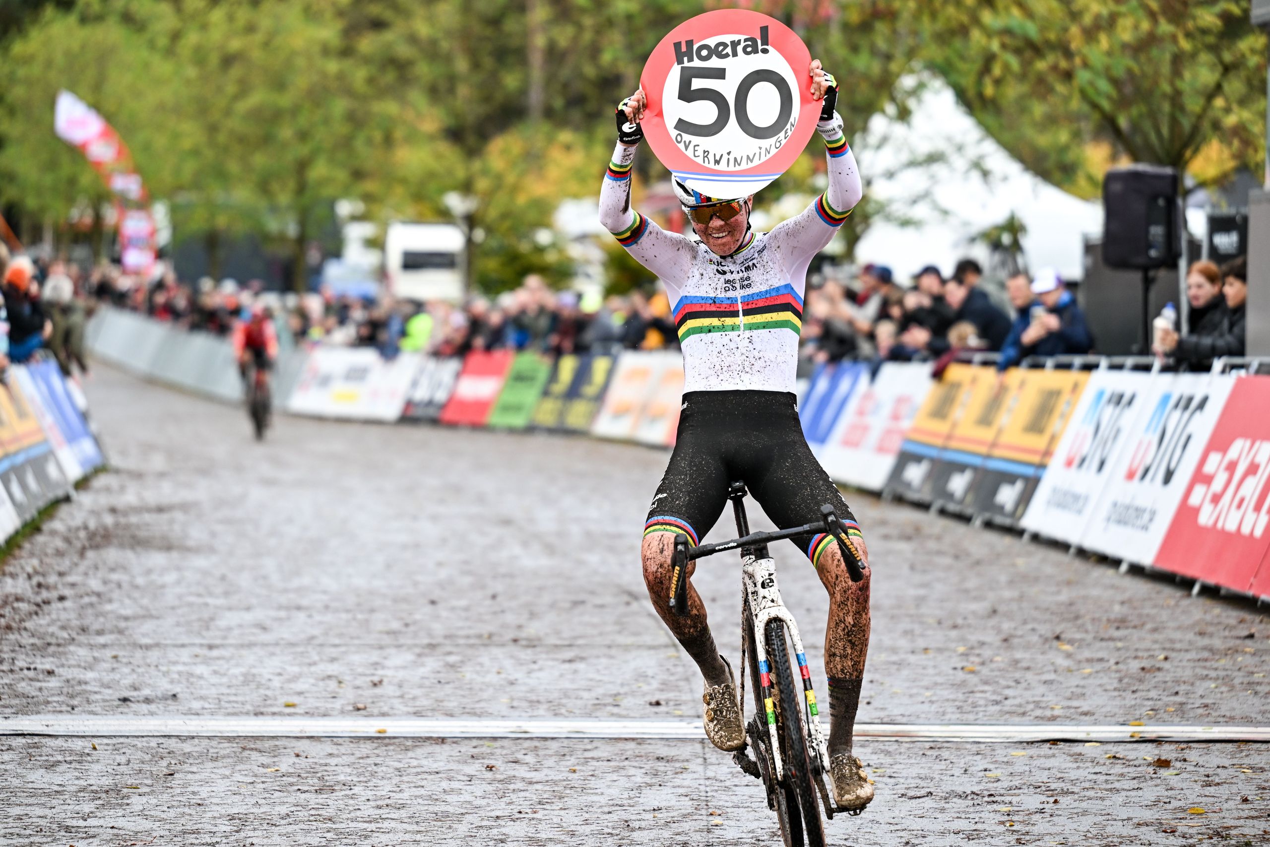 Fem van Empel celebra su victoria número 50 en ciclocross en la embarrada carrera Exact Cross con un cartel hecho a mano escondido en su kit