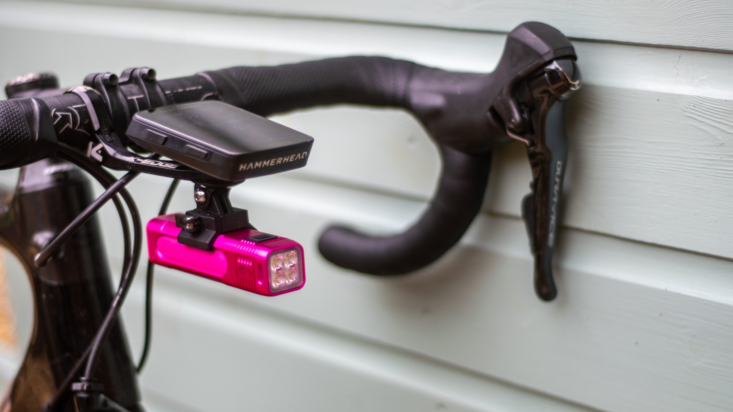 Una luz rosa Knog Blinder montada en una computadora para bicicleta