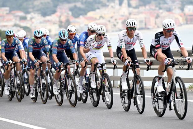 UAE Team Emirates lead Pogačar in a line of riders with the Italian coast out of focus in the background