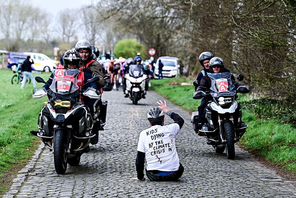 A protestor sits on the road while riders compete in the 'Ronde van Brugge' men's elite one-day cycling race, 202,9 km from and to Bruges on March 25, 2026. (Photo by MAARTEN STRAETEMANS / Belga / AFP) / Belgium OUT