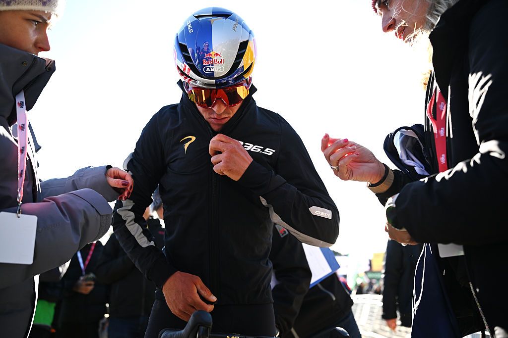 Pidcock zips up a warm jacket while still wearing his Red Bull helmet and glasses