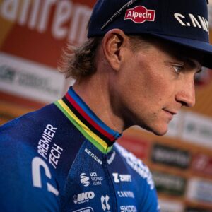 A close profile view of Mathieu van der Poel in his cycling kit with rainbow trimmed neck and a ballcap