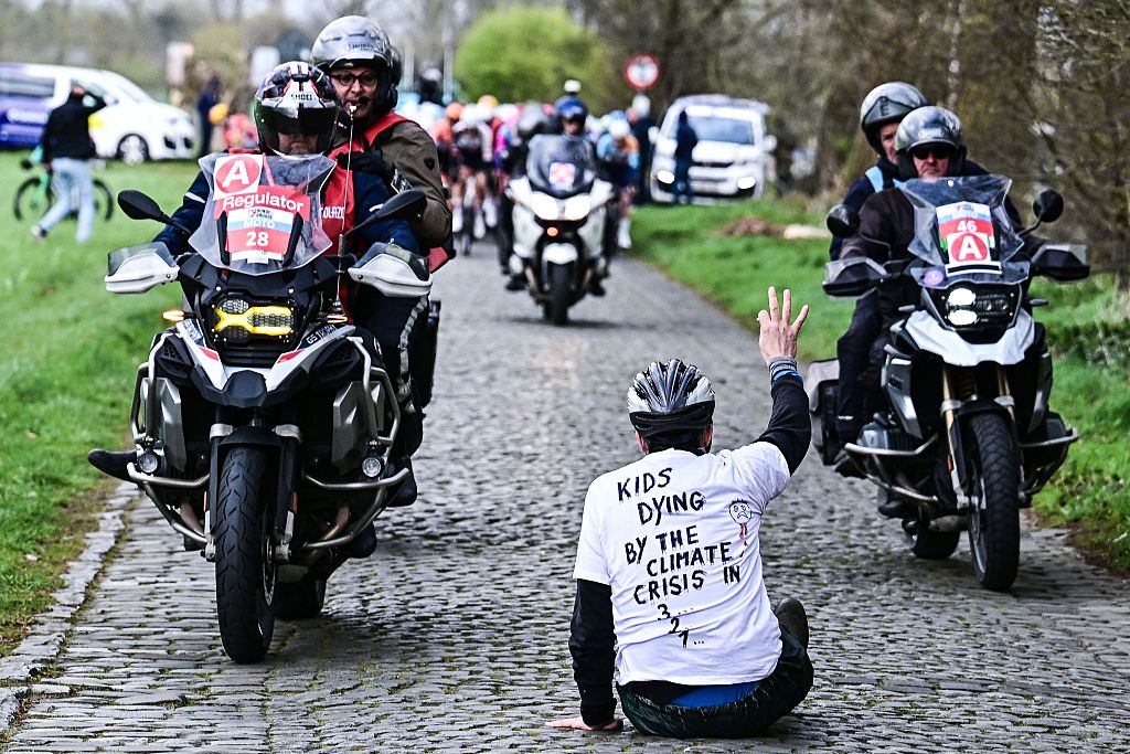 Un manifestante se sienta en la carretera mientras los ciclistas compiten en la 'Ronde van Brugge' Carrera ciclista de élite masculina de un día, 202,9 km desde y hacia Brujas el 25 de marzo de 2026. (Foto de MAARTEN STRAETEMANS / Belga / AFP) / Bélgica FUERA