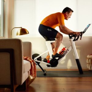 A man rides a Zwift Ride smart trainer in a living room