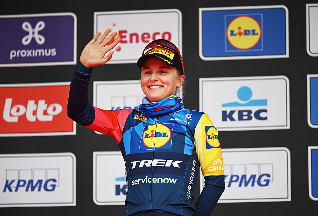 Fleur Moors de Lidl-Trek sube al podio de In Flanders Fields 2026, sonriendo y levantando un brazo, saludando a la multitud