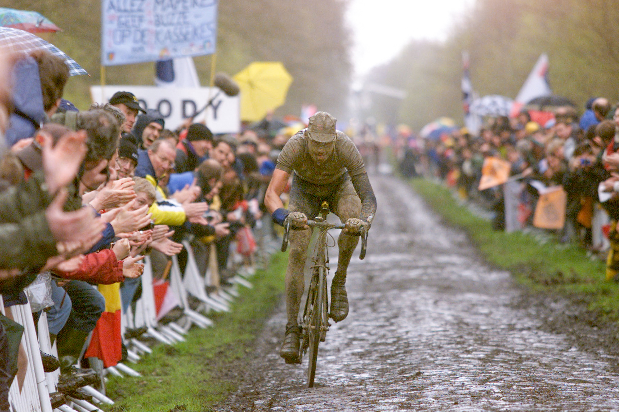 Un embarrado Wilfried Peeters corre por el bosque de Arenberg durante la París-Roubaix de 2001, una de las ediciones icónicas de la historia reciente de la carrera.