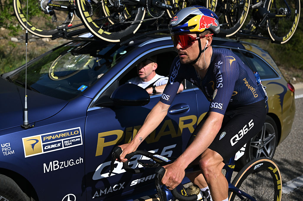 Toma lateral de Tom Pidcock conduciendo junto a su coche del equipo Pinarello-Q35.5 durante una etapa de la Volta a Catalunya