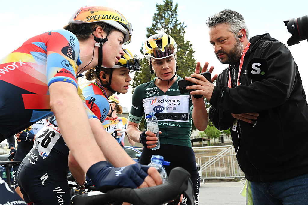 Mischa Bredewold, Anna van der Breggen y Lotte Kopecky observan el sprint en el teléfono de un periodista después de que Kopecky descendiera