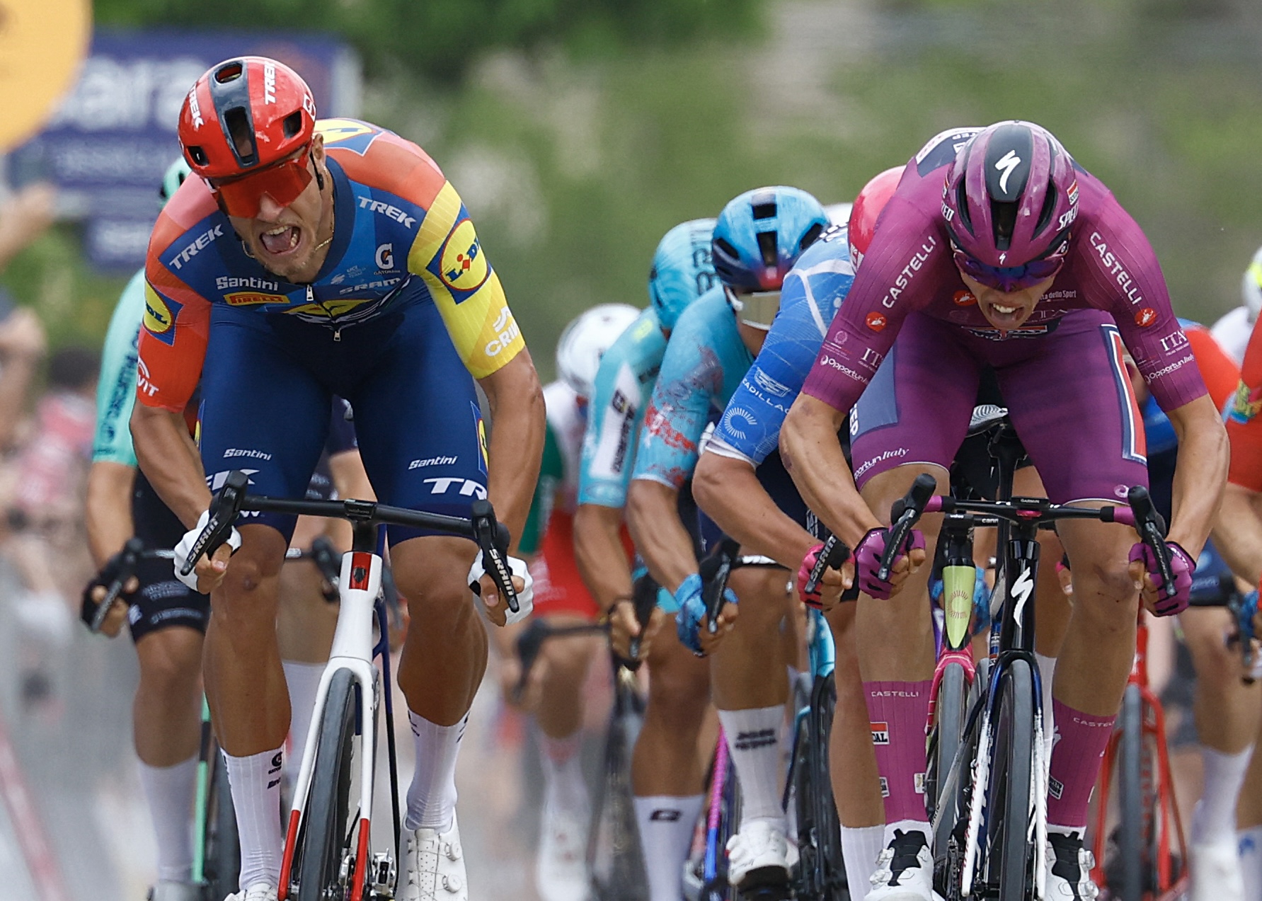 Paul Magnier (C), con el maillot malva de clasificación de puntos (Maglia Ciclamino), celebra su cruce de la línea de meta junto a Lidl - El ciclista italiano de Trek Jonathan Milan