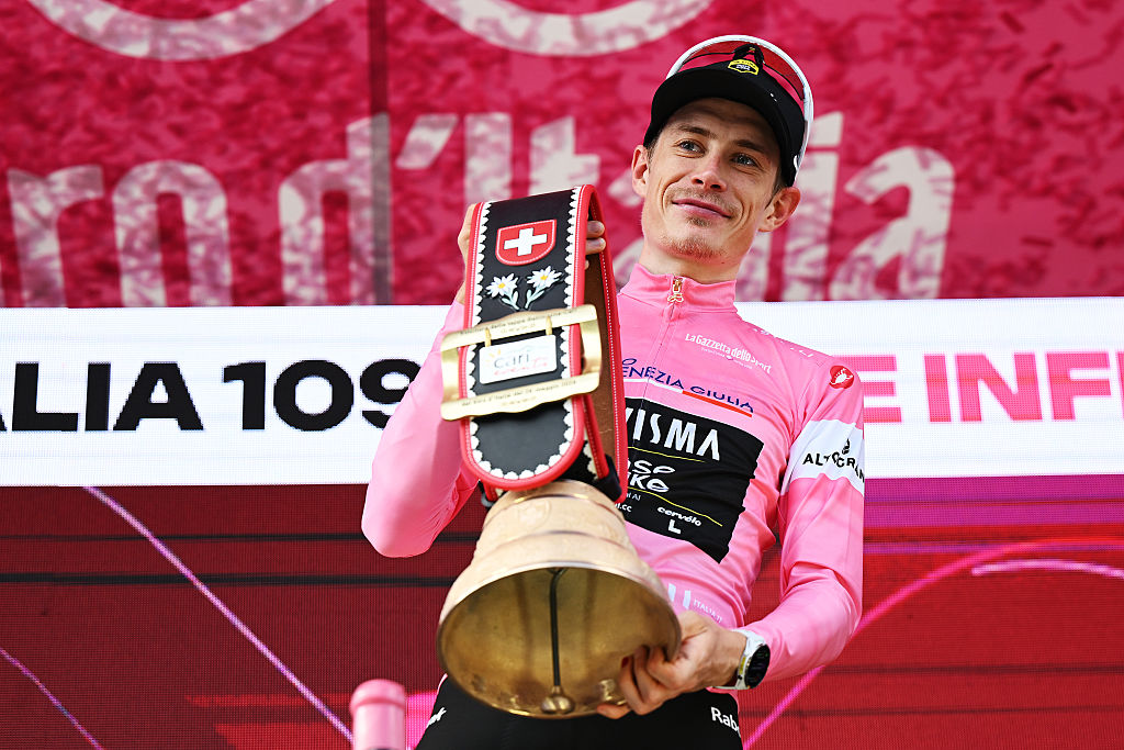 Jonas Vingegaard con la maglia rosa en el podio sostiene una enorme campana como premio de los anfitriones suizos