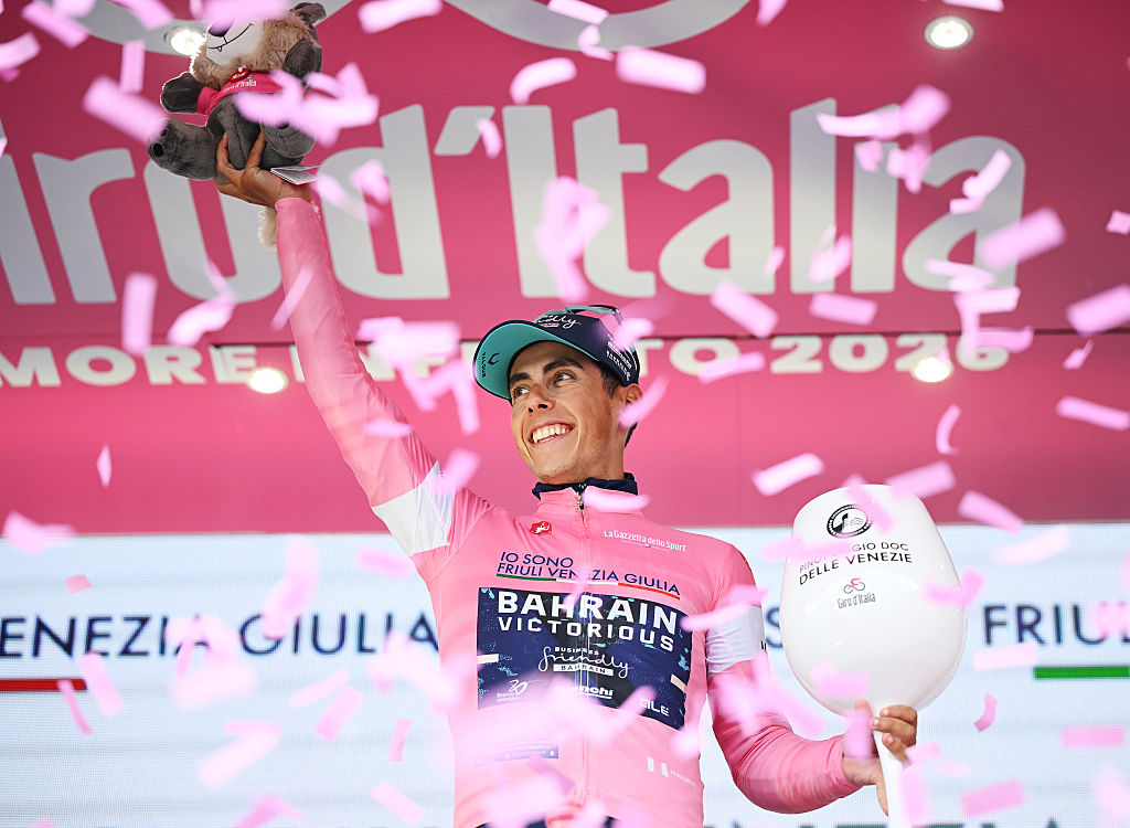 Eulalio celebra en el podio con la maglia rosa mientras cae confeti rosa a su alrededor