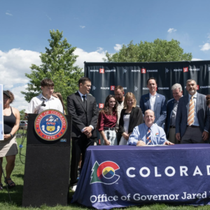 Governor Polis (seated) is joined by advocates and legislators at Valmont Bike Park for the signing of SB26-132 on June 4, 2026