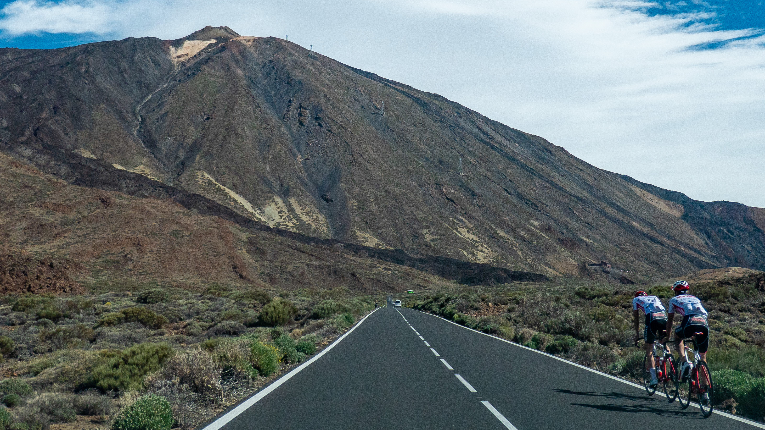 Ciclistas en bicicleta de carretera durante un día de verano con cielo azul alrededor del paisaje volcánico del Volcán El Teide y el Parque Nacional (Foto de Nicolas Economou/NurPhoto vía Getty Images)