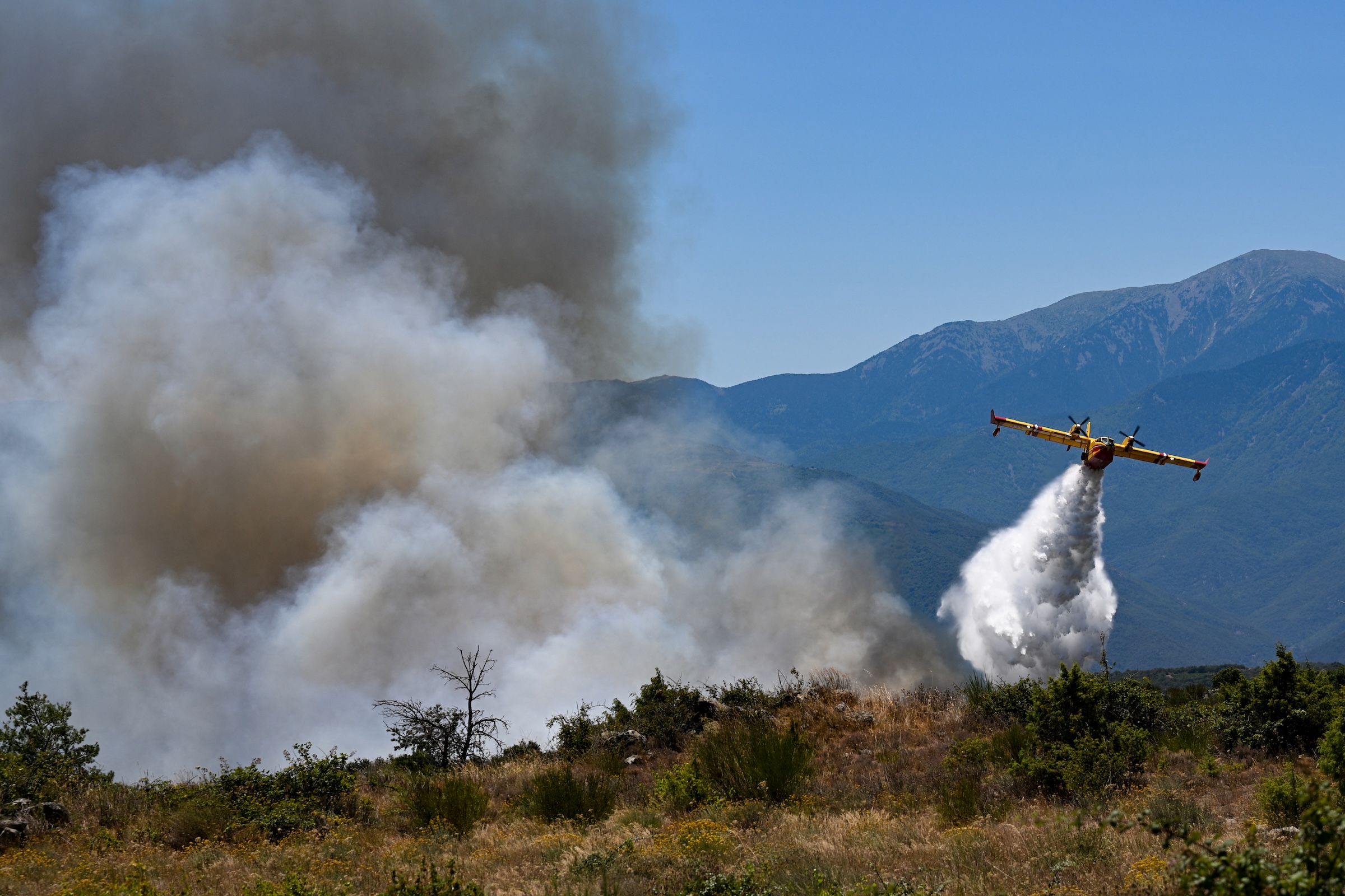 Un avión Canadair CL-415 de los servicios de Seguridad Civil de Francia arroja agua sobre un incendio forestal en Col des Auzines, cerca de Trevillach, en el sur de Francia, el 5 de julio de 2026. 
