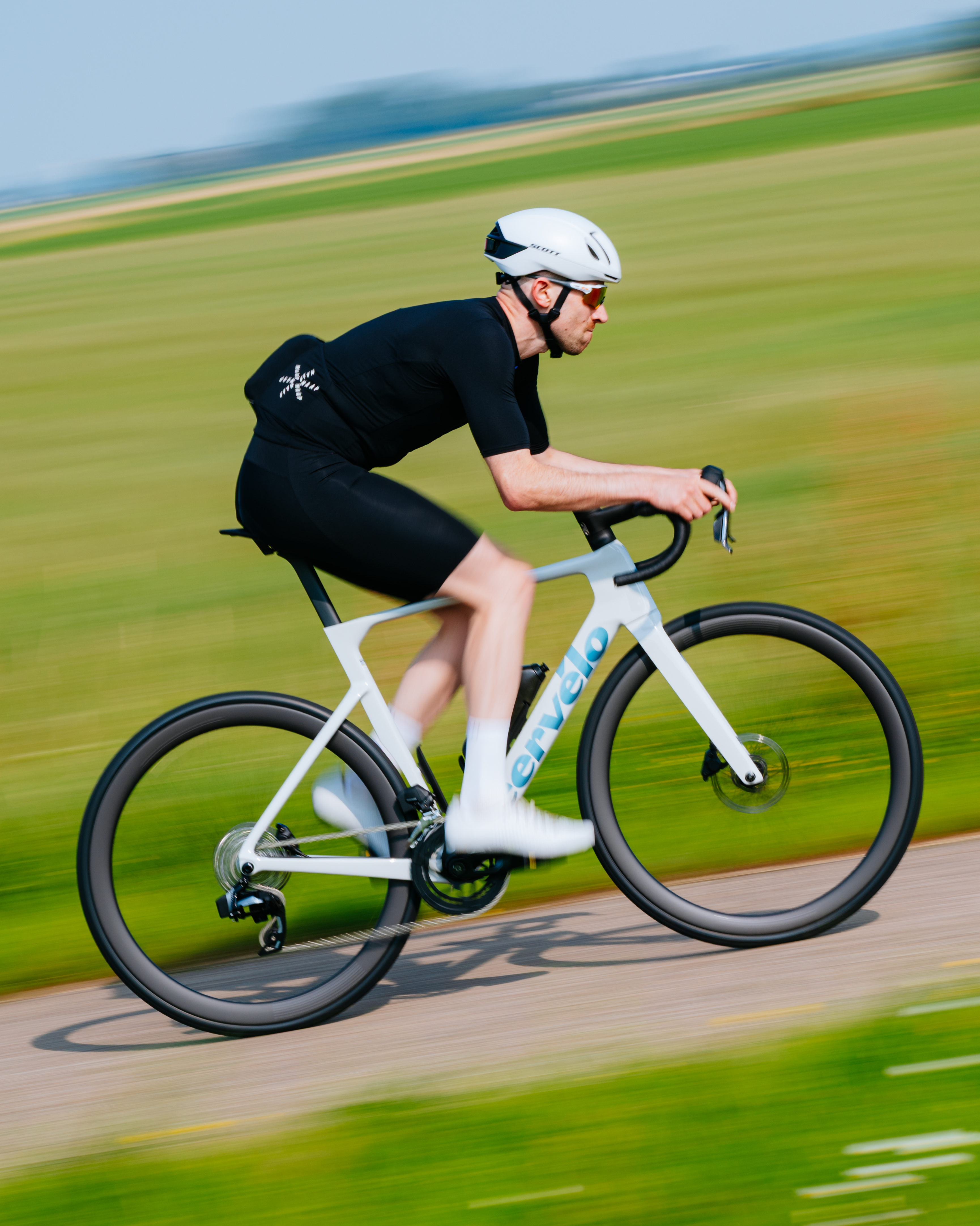Tom montando un Cervélo Soloist blanco frente a campos verdes