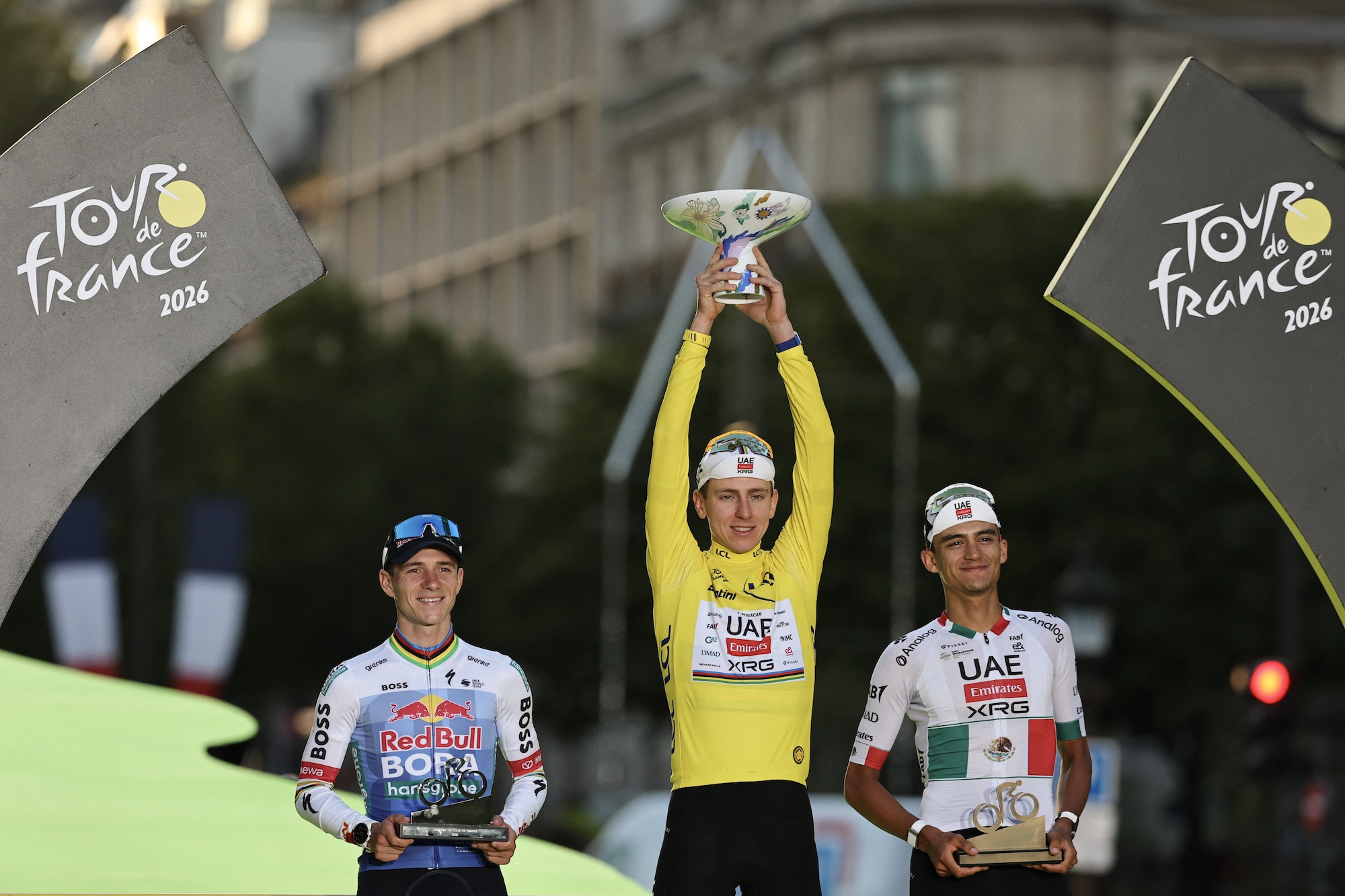 El ganador absoluto del UAE Team Emirates - el ciclista esloveno de XRG Tadej Pogacar celebra en el podio con el segundo clasificado Red Bull - BORA - el ciclista belga del equipo hansgrohe Remco Evenepoel y el tercer clasificado UAE Team Emirates - el ciclista mexicano de XRG Isaac Del Toro después de la 21.ª etapa de la 113.ª edición de la carrera ciclista del Tour de Francia, con 88,7 km de salida y terminando en París, el 26 de julio de 2026. (Foto de Anne-Christine POUJOULAT / AFP)