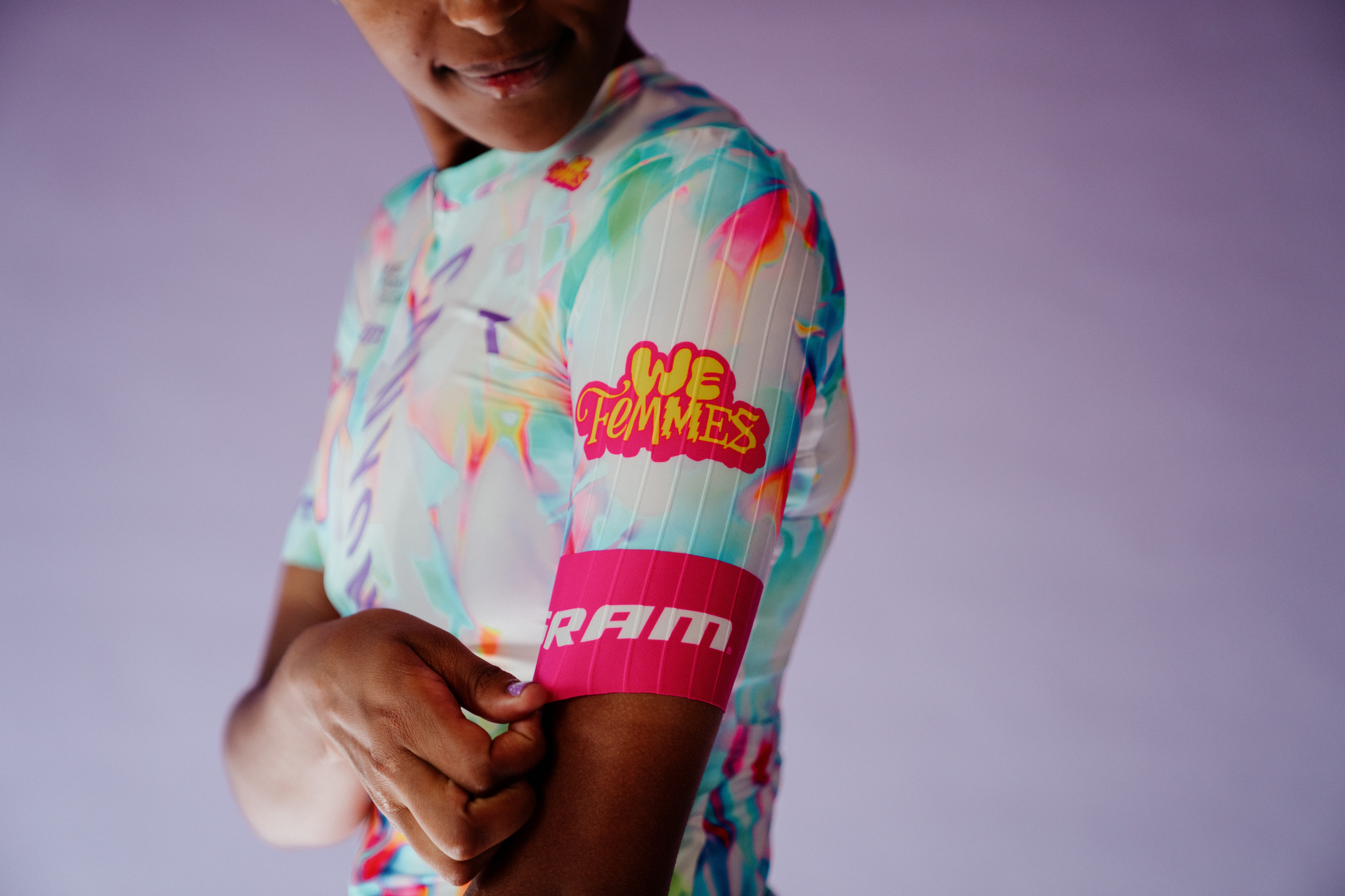 Nuevo kit Canyon-SRAM, que presenta un fondo blanco claro con detalles coloridos en rosa, azul, naranja y verde, además de un kit 'We Femmes' rosa y amarillo. logo