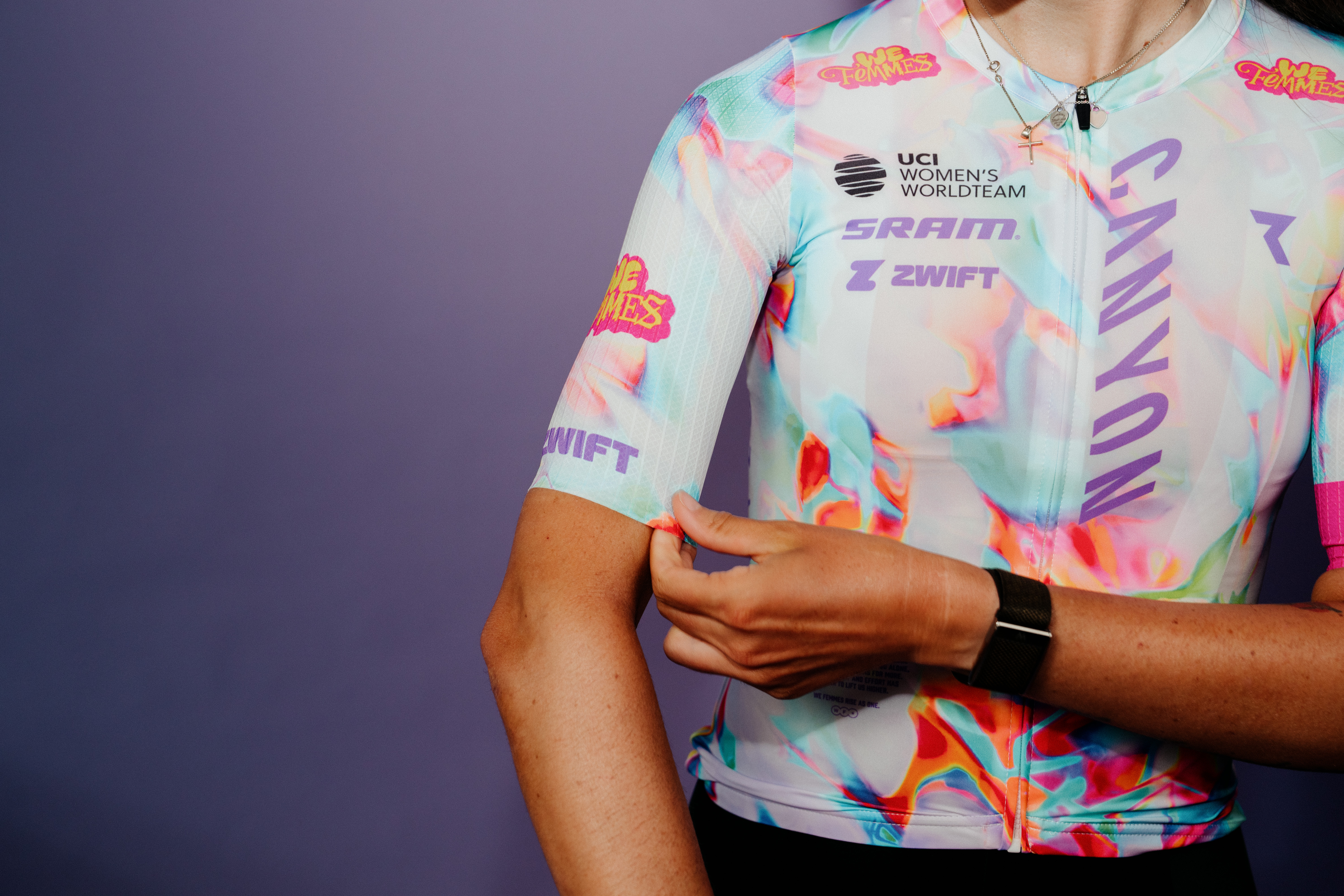 Nuevo kit Canyon-SRAM, que presenta un fondo blanco claro con detalles coloridos en rosa, azul, naranja y verde, además de un kit 'We Femmes' rosa y amarillo. logo