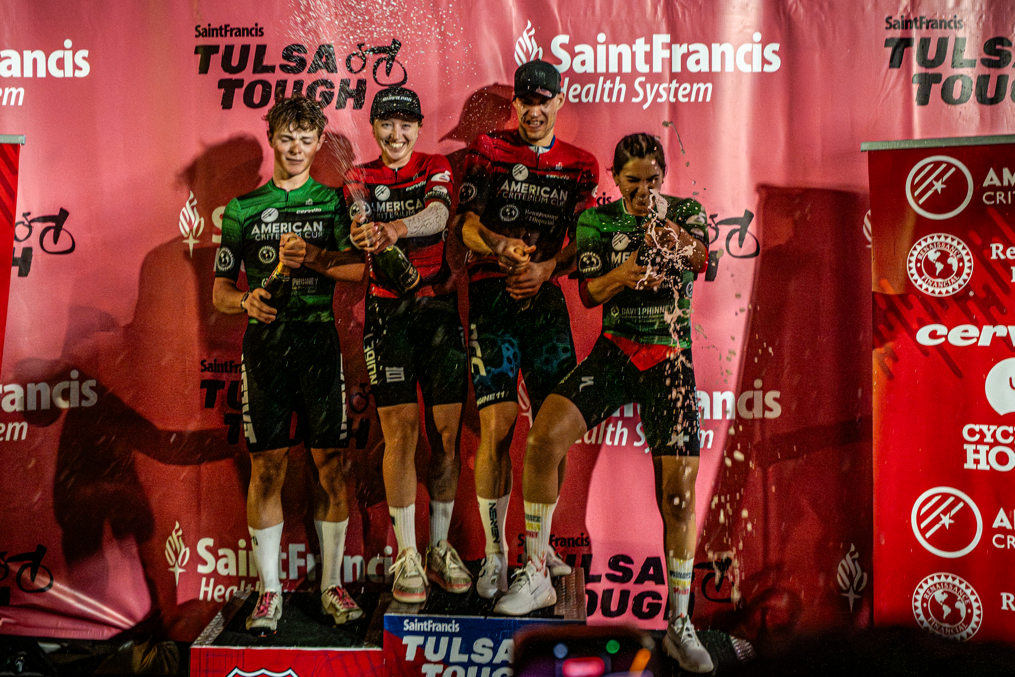 Podio de la American Criterium Cup después del Criterium Blue Dome del grupo McNellie 2026 en Tulsa Fin de semana duro, los ganadores de la carrera Skylar Schneider y Dario Rapps con camisetas rojas de líder