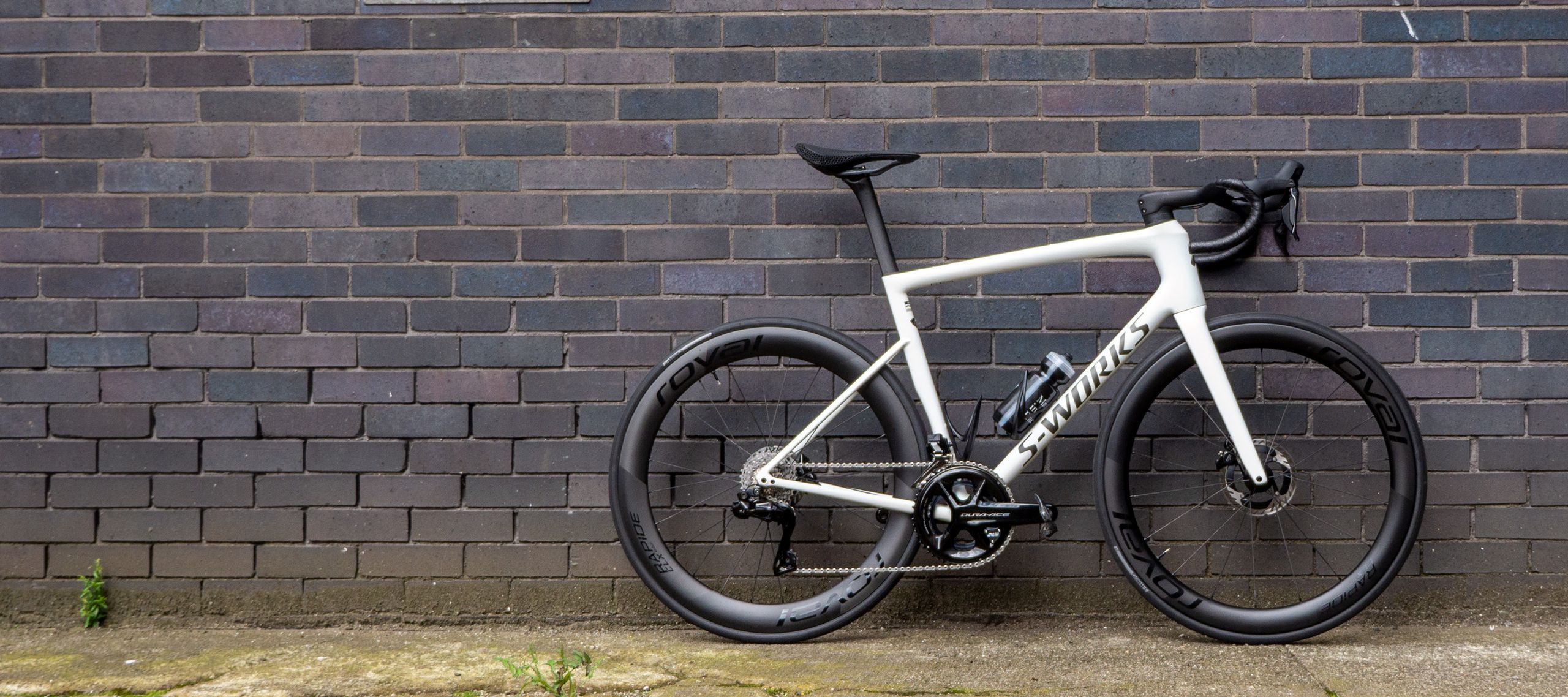 A white Specialized S-Works Tarmac SL8 stands against a wall