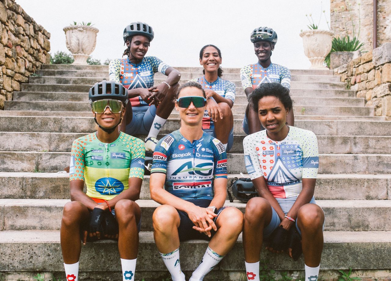 Ashleigh Moolman Pasion sentada junto a los ciclistas del equipo Amani
