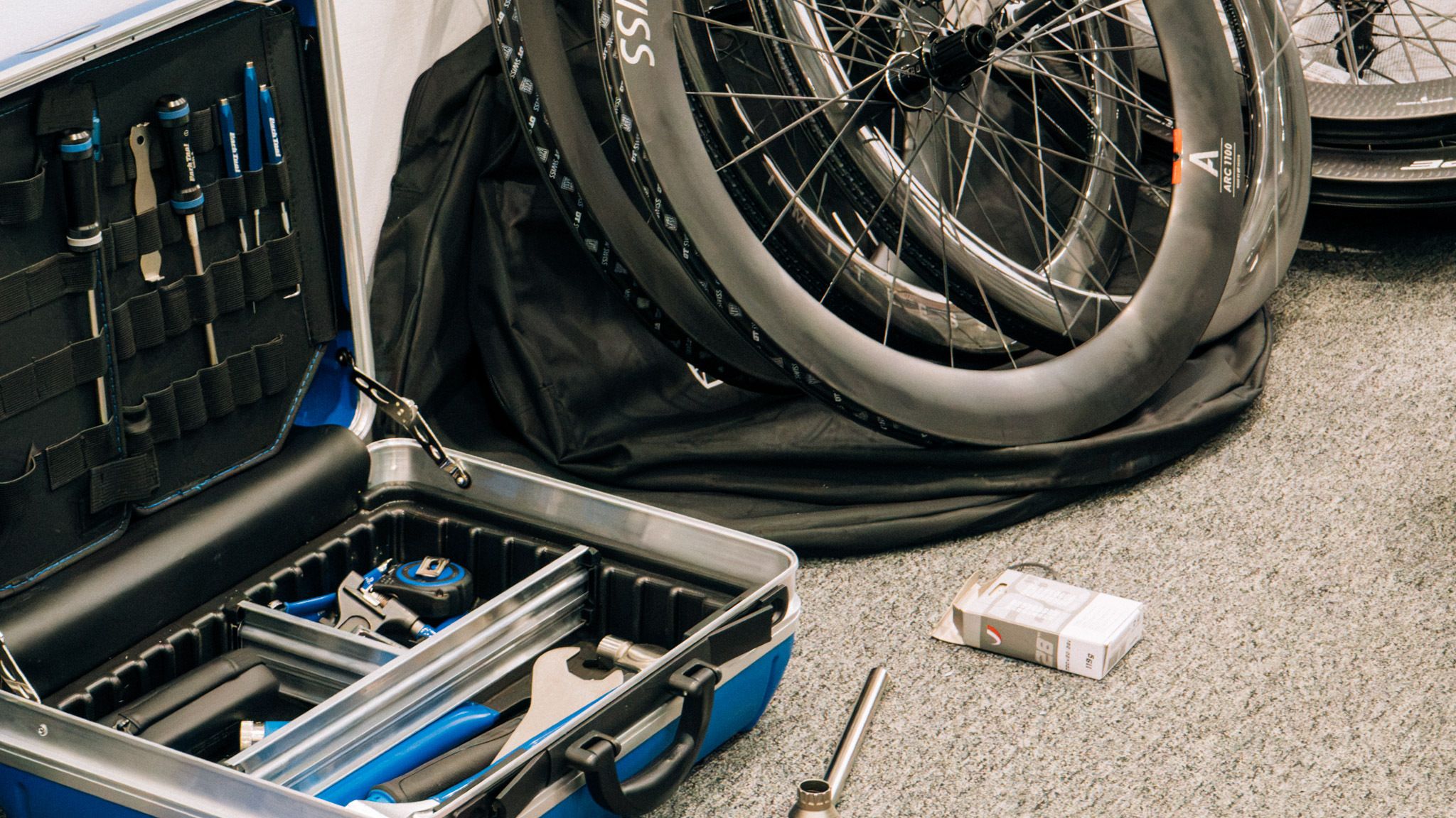 An open toolbox sits next to a pile of road bike wheels