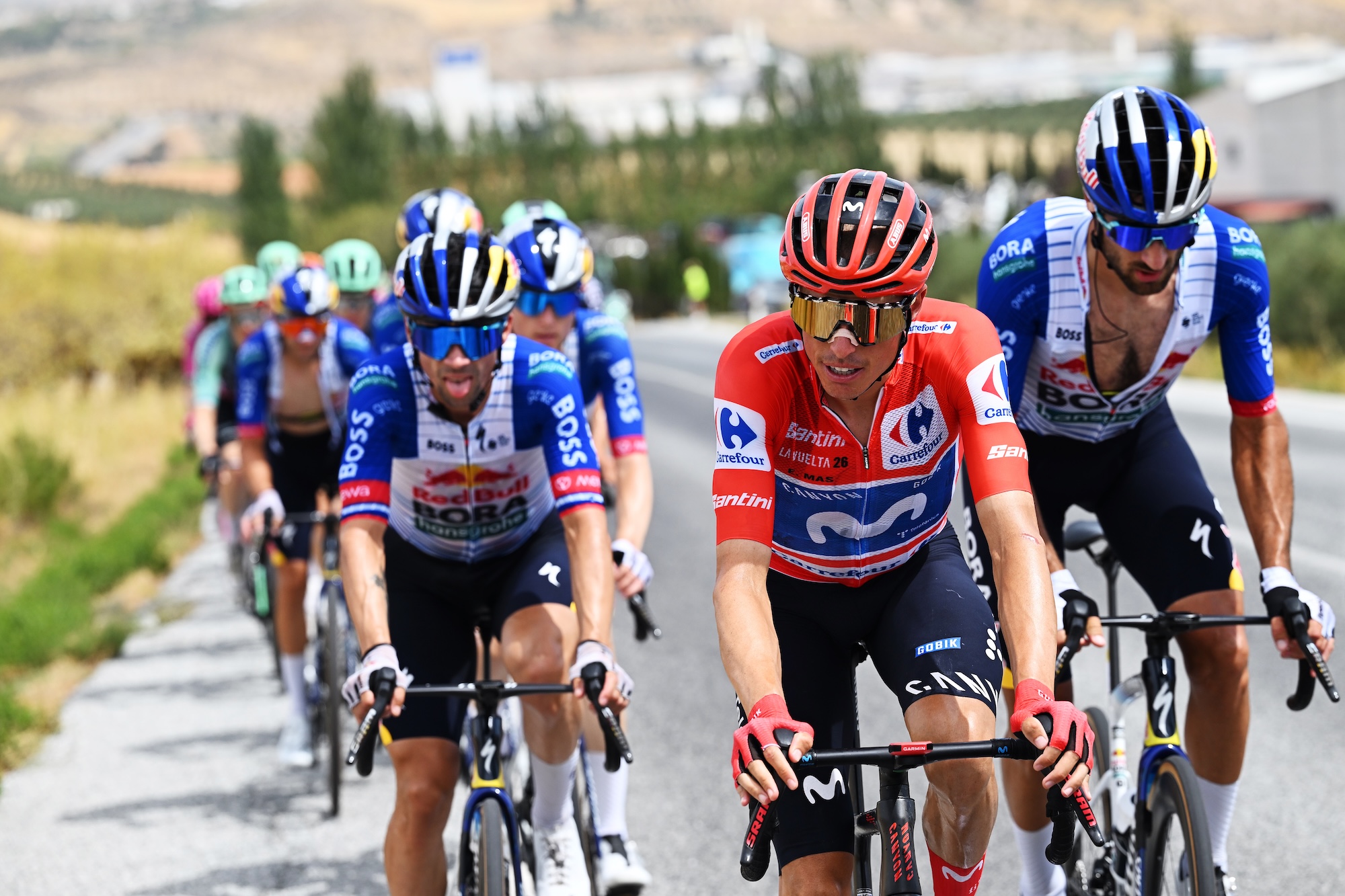 Enric Mas corre con el maillot rojo y detrás los corredores del Red Bull-Bora-Hansgrohe