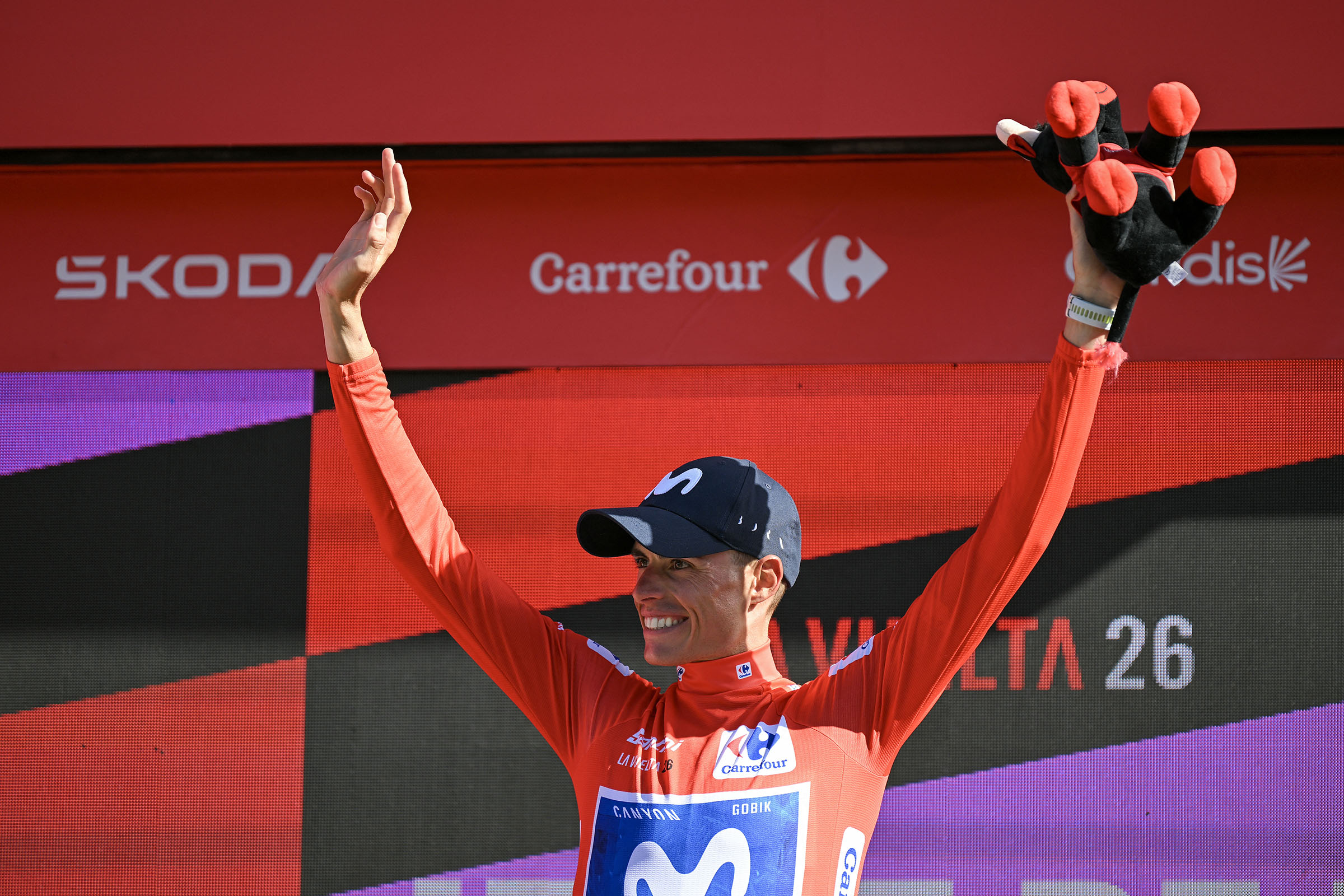 Enric Mas levanta los dos brazos en el podio del maillot rojo