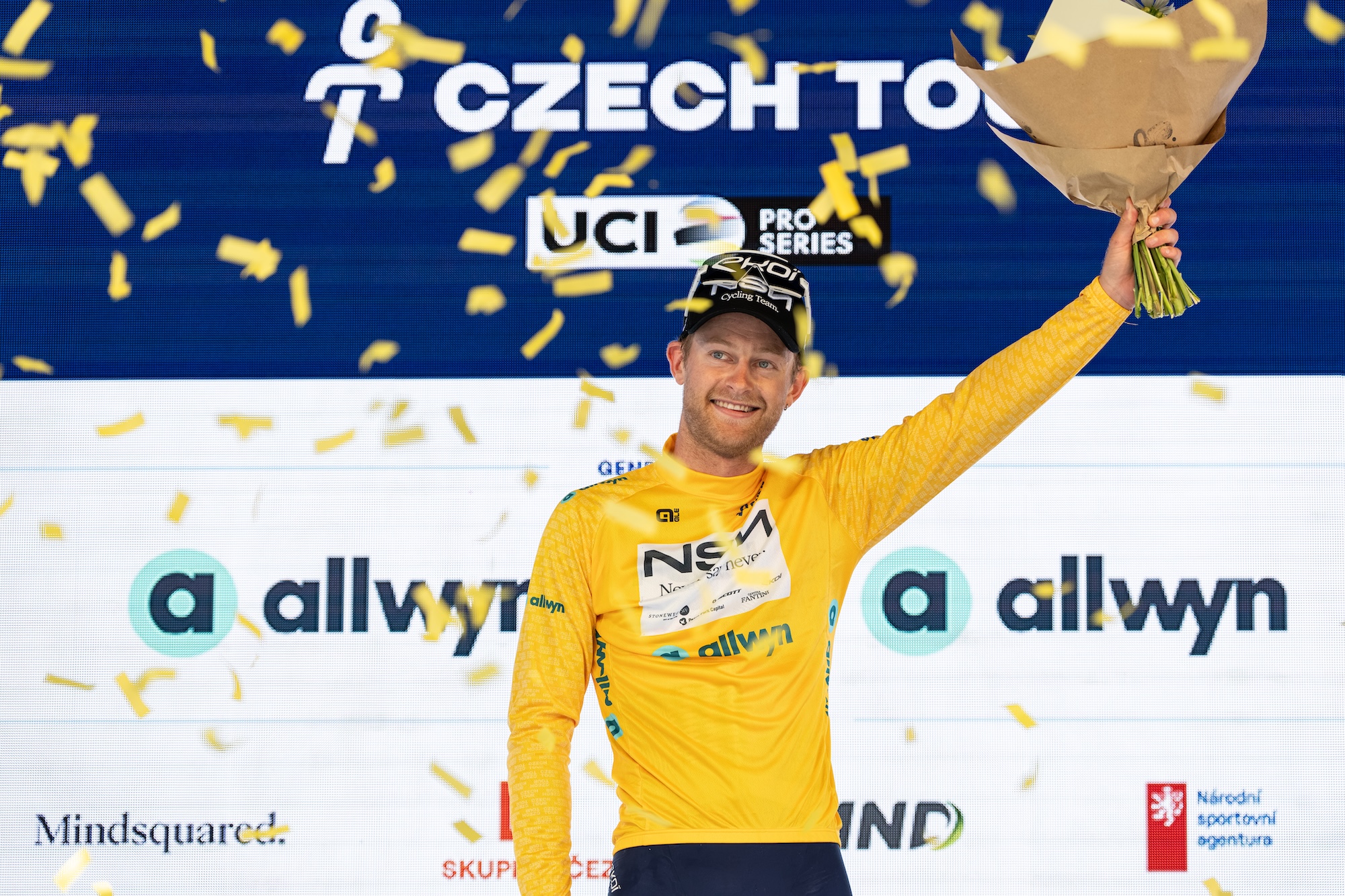 Riley Sheehan del equipo NSN celebra en el podio con el maillot amarillo como líder general tras la etapa 1 del Tour Checo 2026
