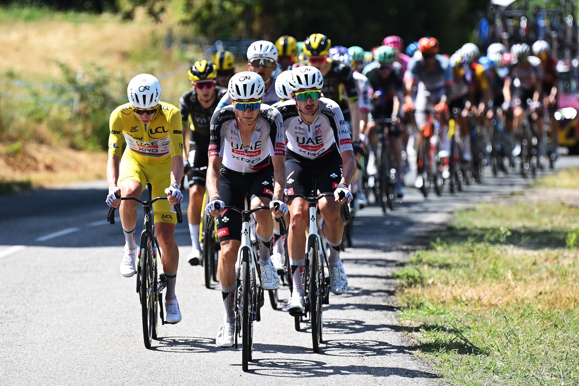 Tadej Pogacar, con la camiseta amarilla de líder, viaja en el pelotón de la etapa 12 junto a sus compañeros del UAE Team Emirates-XRG, Felix Grossschartner y Brandon McNulty.